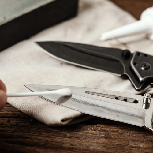 The man oiling his pocket knife. Pocket knife care and maintenance concept.